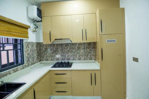 a kitchen with wooden cabinets and a stove top oven at Naya's Apartment: A Lush Ambience (Katampe, Abuja) in Abuja