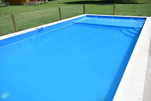 a large blue swimming pool in a yard at Cabañas Cuncumen in Tandil
