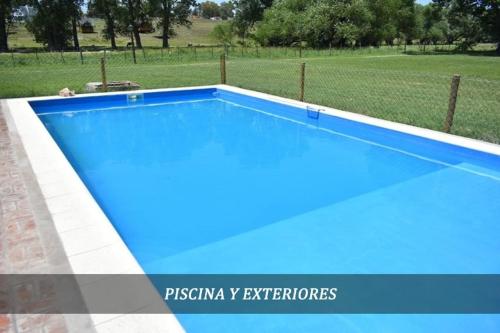 a blue swimming pool with a fence and a field at Cabañas Cuncumen in Tandil