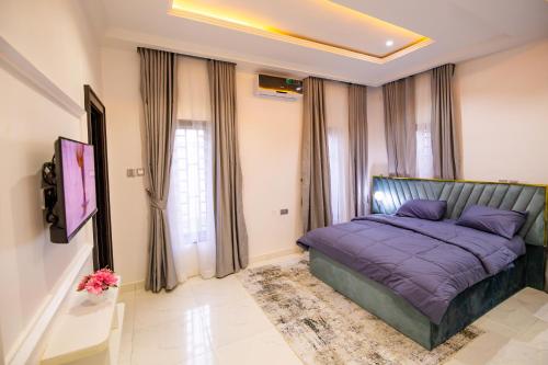 a bedroom with a bed with purple sheets and curtains at Naya's Apartment: A Lush Ambience (Katampe, Abuja) in Abuja
