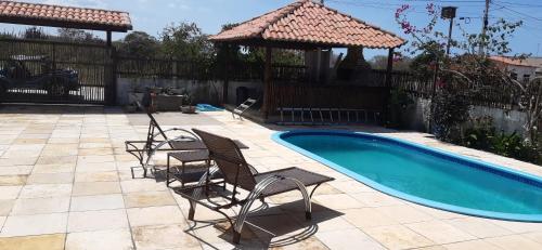 a group of chairs sitting next to a swimming pool at Casa Bete e Farouk in São Miguel do Gostoso