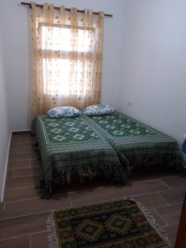 a bedroom with a bed with a curtain and a window at Bujtinat Skenderi Gjinar 2 in Gjinar