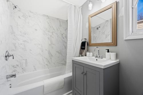 Baño blanco con lavabo, bañera y espejo en Lovely 3 Bedroom Colonial home en Middletown