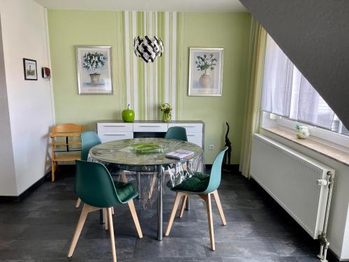 ein Esszimmer mit einem Tisch und grünen Stühlen in der Unterkunft Ferienwohnung Friesennest Greetsiel 1 in Krummhörn