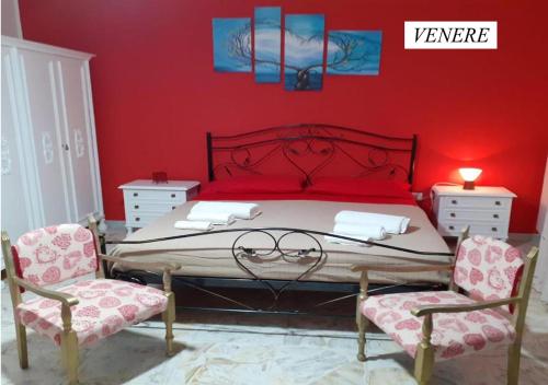 um quarto vermelho com uma cama e 2 cadeiras em Il Rifugio di Bacco e Venere em Pietrapertosa