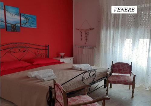 um quarto vermelho com uma cama e 2 cadeiras em Il Rifugio di Bacco e Venere em Pietrapertosa