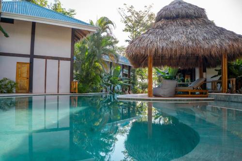 a resort with a swimming pool and a thatch hut at Blue Mist Hotel- Adults Only in Santa Teresa Beach