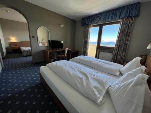 a hotel room with a large bed and a window at PanoramaHotel Penegal in Mendola