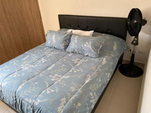 uma cama com um edredão azul e uma ventoinha em Sunset Flat - Apartamento Amoblado em Playa Dormida