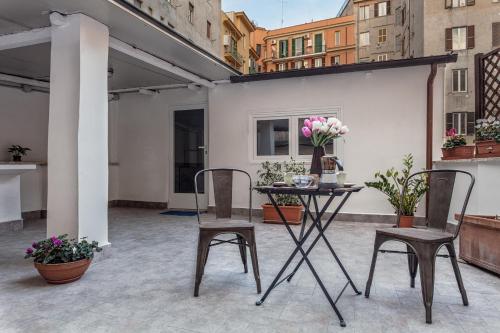 un patio con 2 sillas y una mesa con flores en Roma Capoccia in Vaticano, en Roma