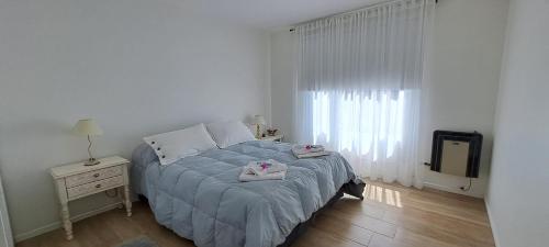 a white bedroom with a bed and a television at Ventanas de la Patagonia in Esquel