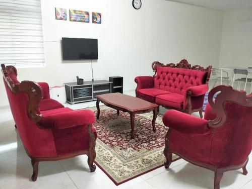 a living room with two red chairs and a tv at Mahzan Homestay in Jitra