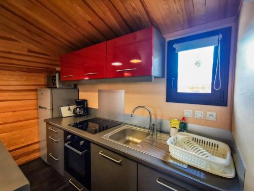 een keuken met rode kasten, een wastafel en een aanrecht bij PRL Le Védrignans - PRL El Pastural in Saillagouse