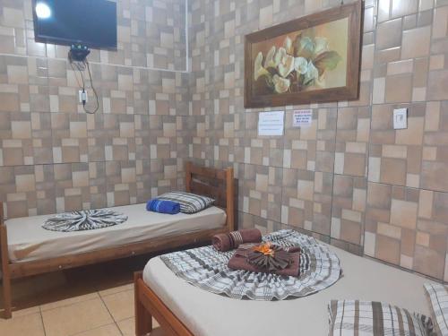 two beds in a room with a tv on the wall at Pousada Castro in Aparecida