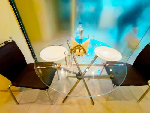 a glass table with two chairs and a bottle on it at SAI SRUSHTI by NEEM SQUARE in Shirdi