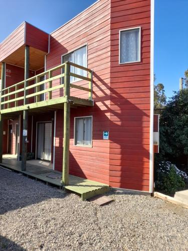 Una casa roja con una escalera en el lateral. en Cabanas Viento Sur. Los Vilos, en Los Vilos