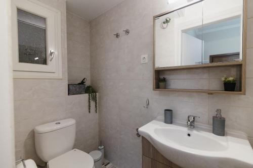 uma casa de banho com um WC, um lavatório e um espelho. em Vivian's cozy apartment em Lárissa