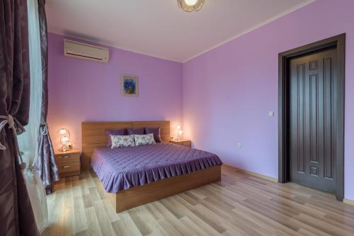 a bedroom with purple walls and a bed with two lamps at Infinity View Shkorpilovci in Shkorpilovtsi