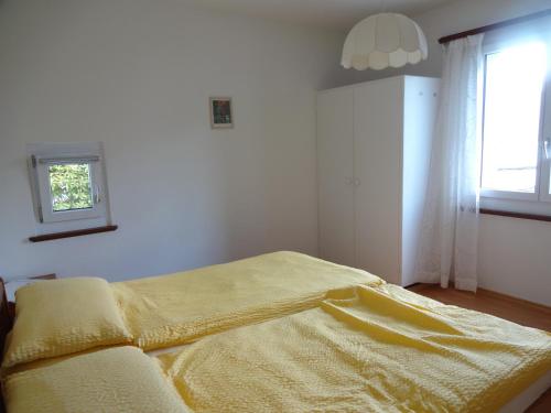 ein Schlafzimmer mit einem Bett mit einer gelben Decke darauf in der Unterkunft Residenza Paradiso di Vacanze in Locarno