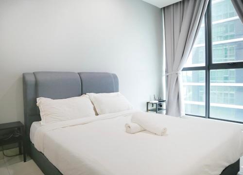 a white bed in a room with a large window at Atria SOFO Suites By Stay In in Petaling Jaya