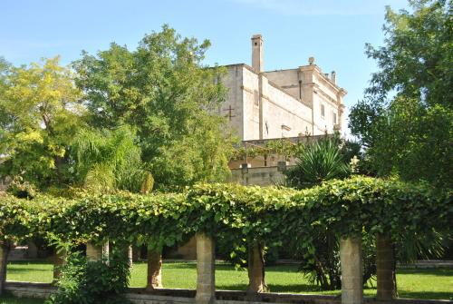 an old building behind a hedge in a park at Castello di Casamassella - Marea Stays Collection in Casamassella