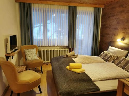 ein Hotelzimmer mit 2 Betten und einem Stuhl in der Unterkunft Apartments Helsen in Mühlbach am Hochkönig