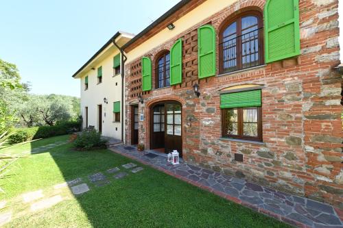 een bakstenen gebouw met groene luiken en een tuin bij Agriturismo Corte Stefani in Capannori