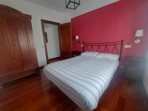 een slaapkamer met een groot bed met een rode muur bij Casa de los sueños in Cadiñanos