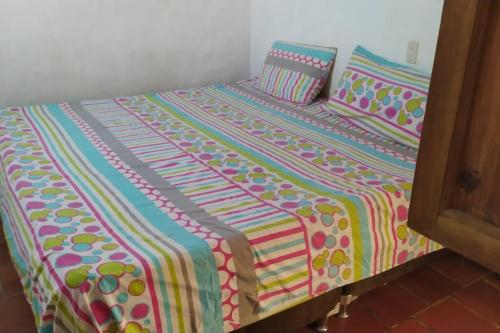 Una cama con una manta colorida y almohadas. en Casa Bari Bari en Barichara