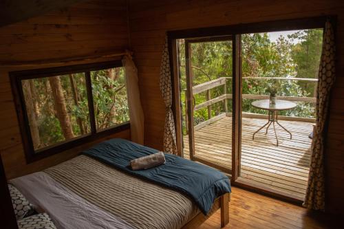 a bedroom with a bed and a balcony with a table at Casa Atipika in Curanipe