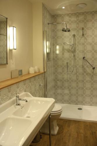 a bathroom with a sink and a toilet and a shower at The Bell Hotel, Saxmundham in Saxmundham