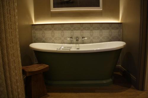 Habitación con baño con bañera verde. en The Bell Hotel, Saxmundham en Saxmundham