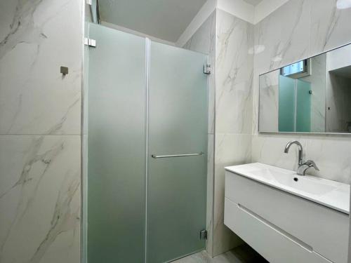 een witte badkamer met een douche en een wastafel bij sea view apartment in Bat Yam