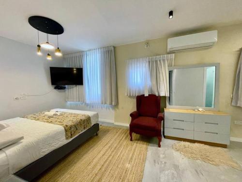 a bedroom with a bed and a chair and a television at sea view apartment in Bat Yam