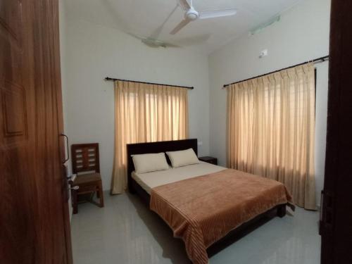 Schlafzimmer mit einem Bett, einem Stuhl und Fenstern in der Unterkunft Eve's Residency in Meppādi