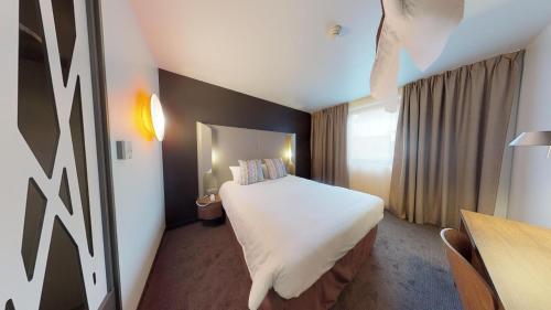 フォンテーヌブローにあるCampanile Fontainebleauの大きなベッドとデスクが備わるホテルルームです。