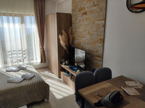 een slaapkamer met een bed en een tafel en een bakstenen muur bij Apartman Adelfes P16, Milmari Resort in Kopaonik