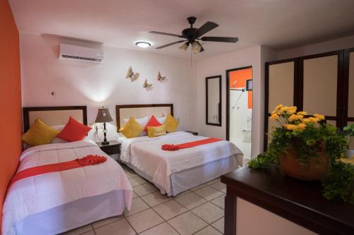 a bedroom with two beds and a ceiling fan at Posada Mariposa Boutique Hotel - 5th Avenue in Playa del Carmen
