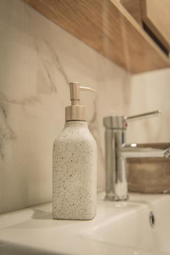 a soap bottle sitting on top of a sink at Artemis Apartment Midas Home Project in Thessaloniki