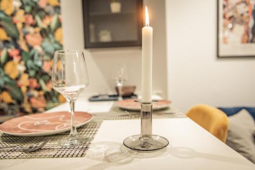 a candle on a table with glasses and a candle holder at Artemis Apartment Midas Home Project in Thessaloniki