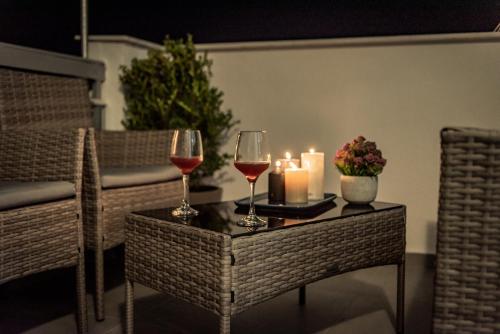 two glasses of wine and candles on a table at Artemis Apartment Midas Home Project in Thessaloniki