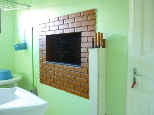 una chimenea de ladrillo en la esquina de un baño en Casa para aluguel de veraneio em Torres, en Torres