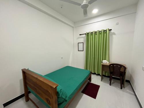 a room with a bed and a green curtain at Victory's Gardens in Mannar