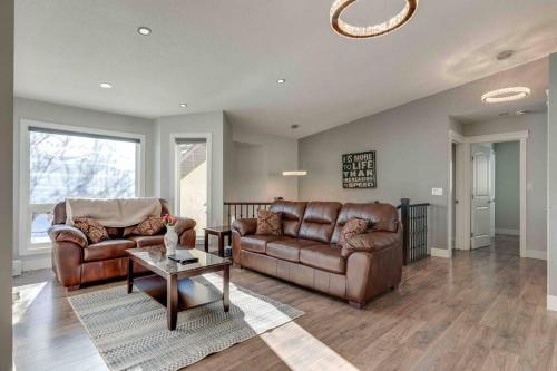 a living room with two leather couches and a table at Rare Find fully renovated 6 bedroom 3 bath and both levels in Calgary