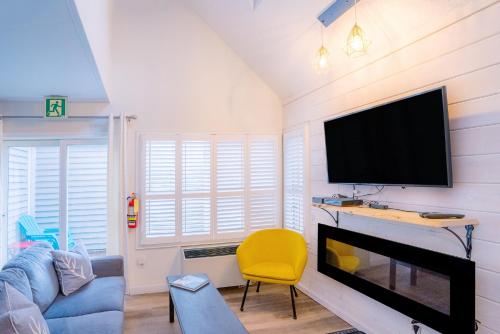 a living room with a flat screen tv and a yellow chair at Loft with a view of Blue - Free Wifi, Linens and Towels Included in Blue Mountains