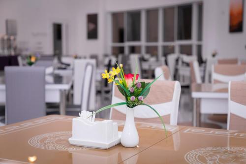 un vaso bianco con fiori su un tavolo di AL shoroq Green Resort a Ghubrat Ţanūf