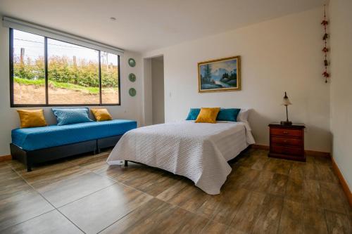 een slaapkamer met een bed en een blauwe bank bij Casa El Roble paipa in Paipa