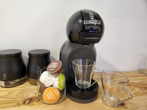 a black coffee maker sitting on a wooden table with glasses at East Park Inn in Polokwane