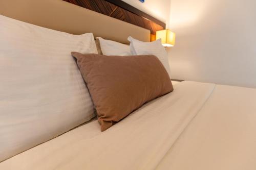 a bed with white sheets and a brown pillow on it at Hotel Best Night 2 in Alger