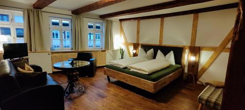 a bedroom with a bed and a table and windows at Traditions - Hotel "Zur Tanne" in Wernigerode
